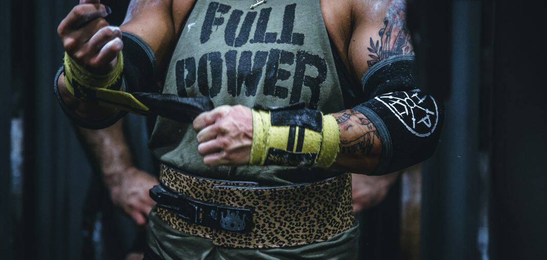 Person wearing athletic gear, including gloves and a tank top that says "FULL POWER."