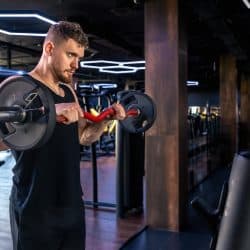 Young athletic man swinging his arms with a barbell in the gym. Sport lifestyle. . High quality photo