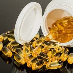 Close-up view of a spilled container of golden capsules or pills, likely dietary supplements or vitamins.