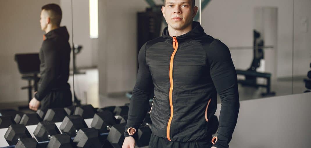 Sports man in the gym. A man performs exercises. Guy with dumbbells.