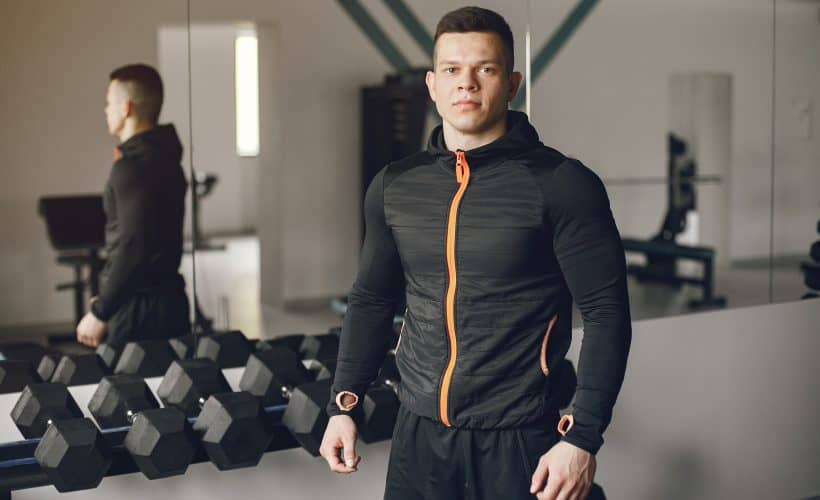 Sports man in the gym. A man performs exercises. Guy with dumbbells.