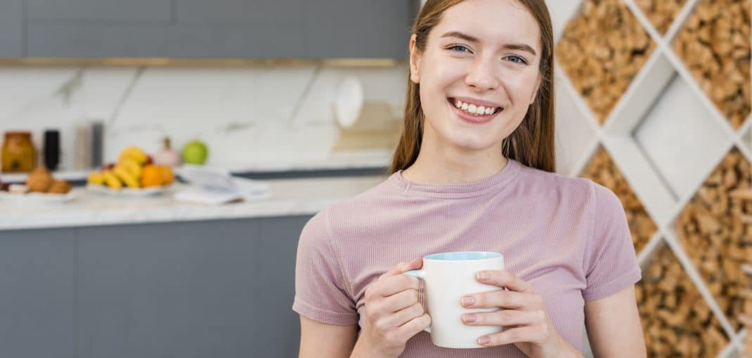 Happy woman holding mug in the kitchen