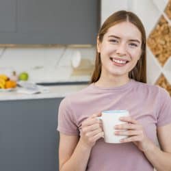 Happy woman holding mug in the kitchen