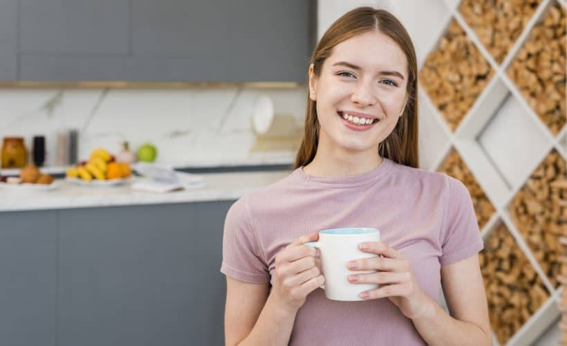 Happy woman holding mug in the kitchen