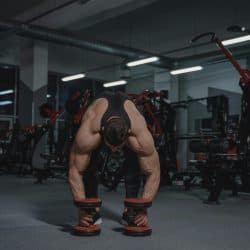 Muscular man lifting weights in a gym surrounded by fitness equipment, highlighting strength training in a professional setting.