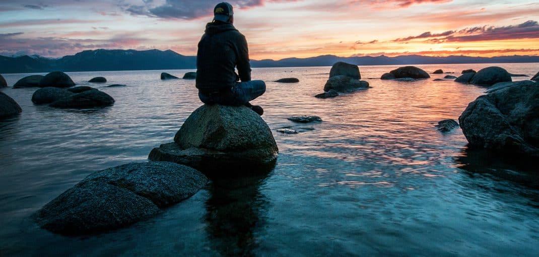 Man sitting on rock surrounded by water