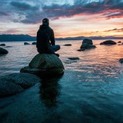 Man sitting on rock surrounded by water