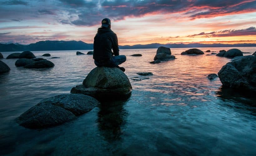 Man sitting on rock surrounded by water