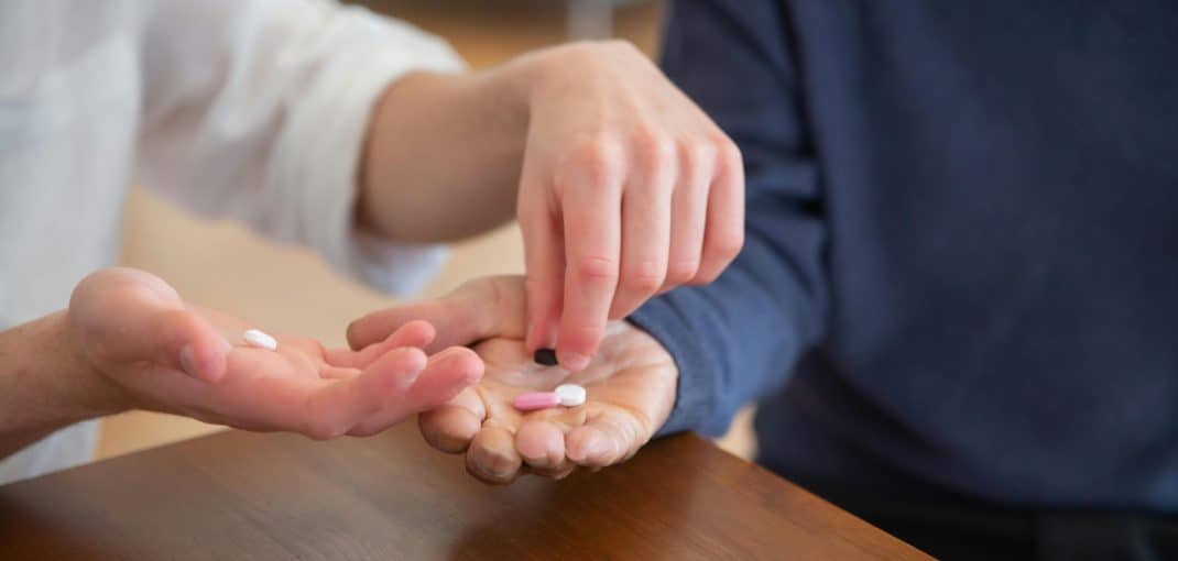 Two people exchanging pills