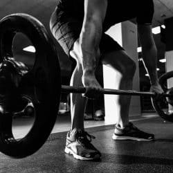 Closeup of weightlift workout at the gym with barbell. Man wearing sportswear clothes.